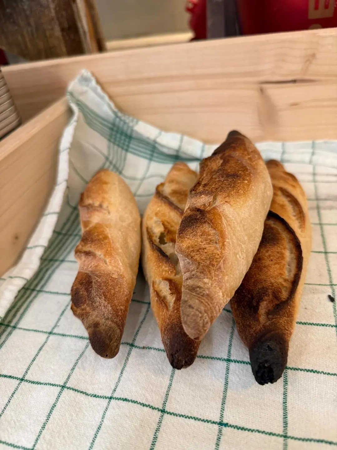 Baguettes in einer Holzkiste auf einem karierten Tuch