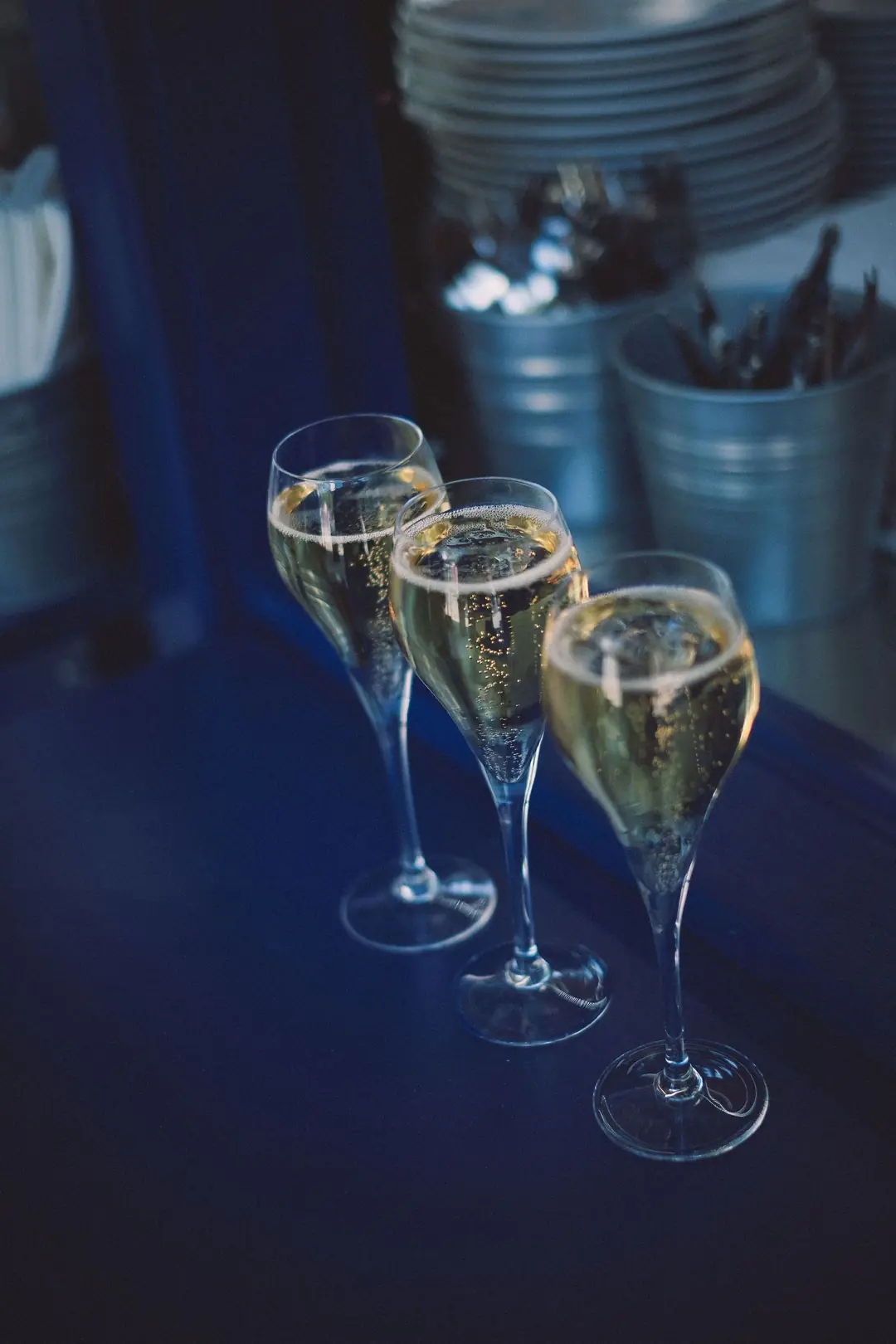 Drei Gläser Champagner auf einem tiefblauen Tisch
