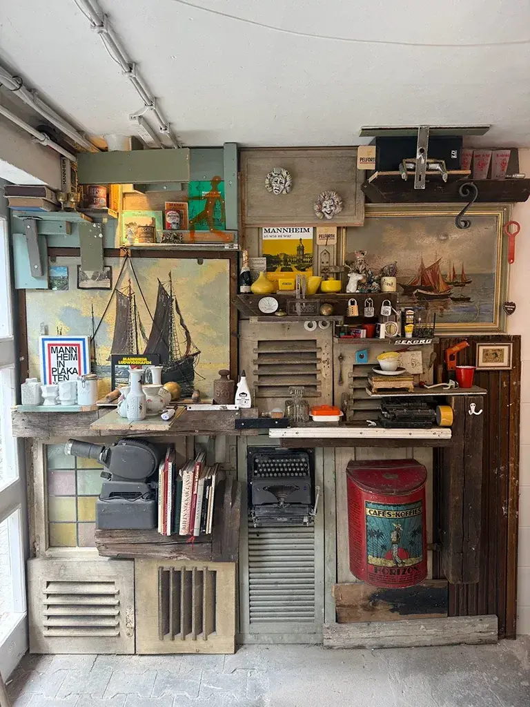 Eine Wand voller Fundstücke: Segelschiff-Gemälde, Schreibmaschine, alte Dosen
