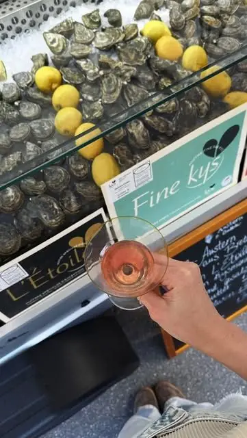 Austern und Zitronen in der Kühlvitrine, davor ein Glas Rosé